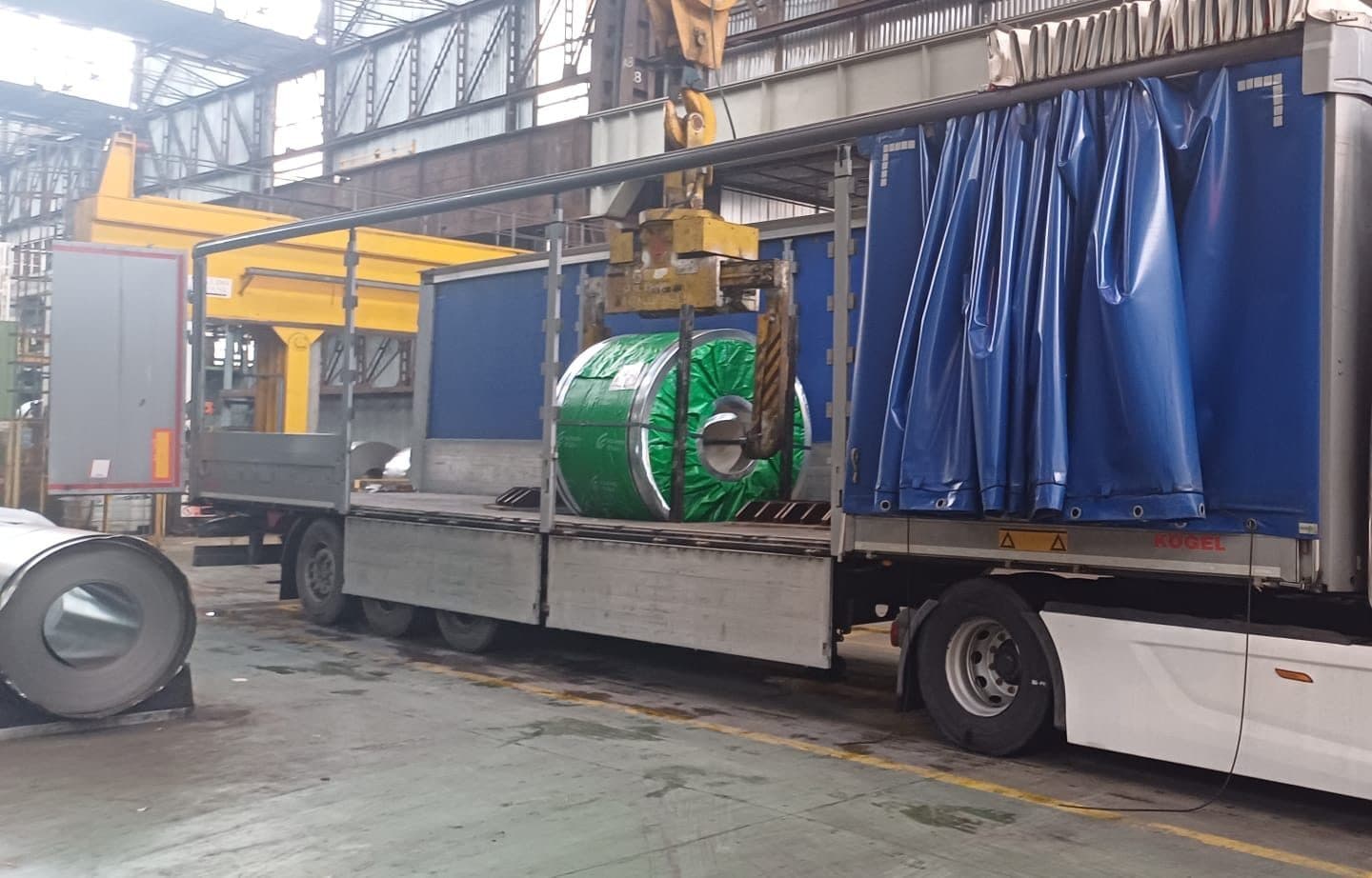 Coil di acciaio calato dal carroponte nella culla portacoils del semirimorchio, dentro l'acciaieria