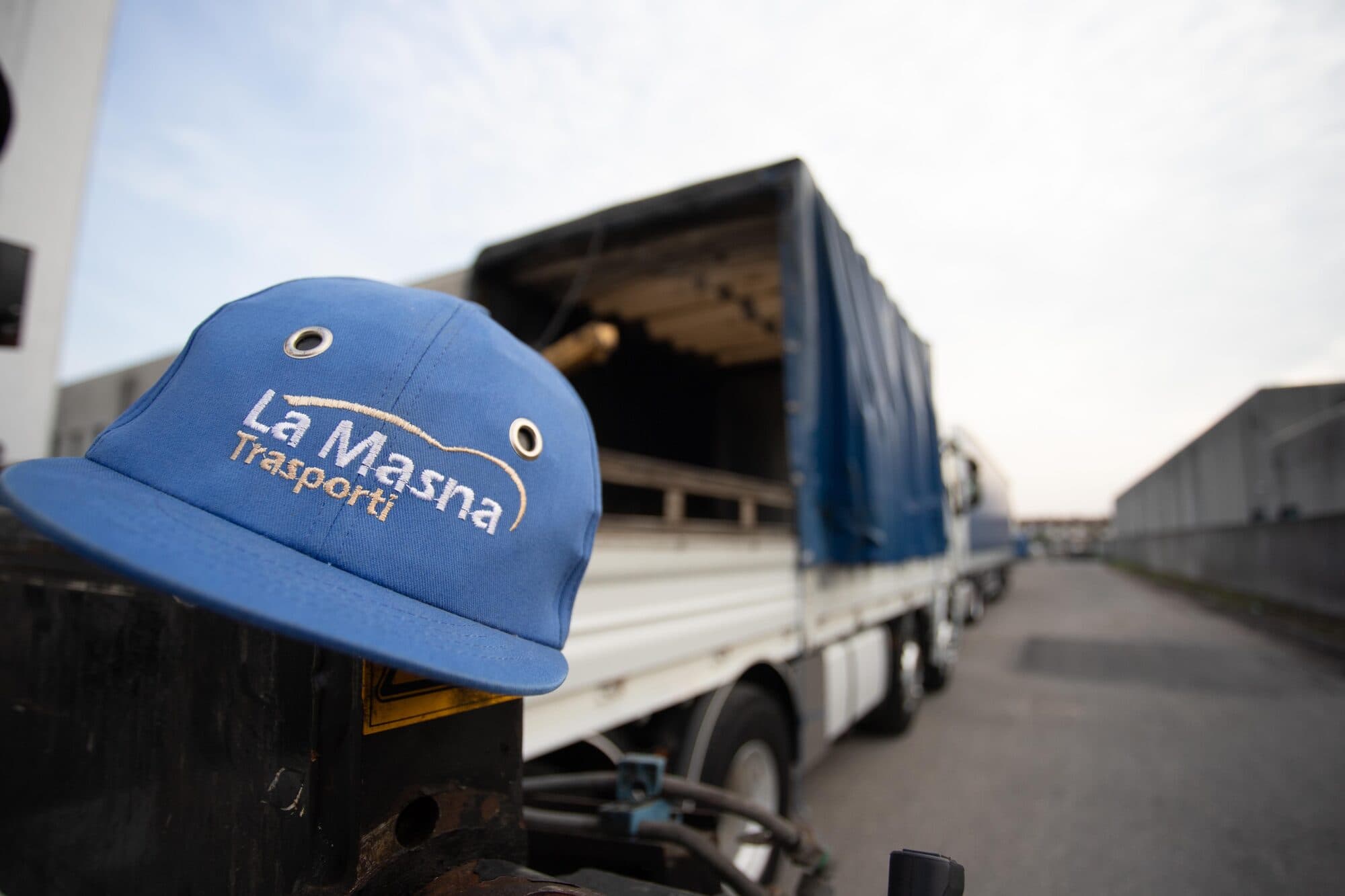 Cappellino con il marchio La Masna Trasporti appoggiato sul braccio della gru